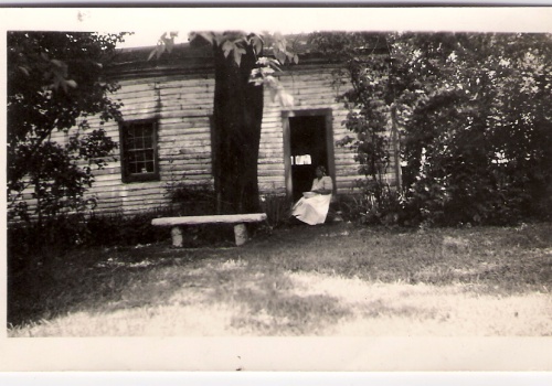 A woman sitting in front of a former slave cabin